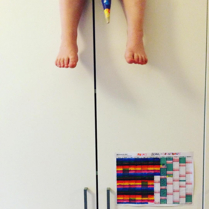Tochter spielt auf dem Schrank mit der Schult&uuml;te des Bruders. Unten h&auml;ngt ihr Schul-Countdown-Kalend